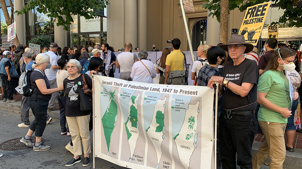 تجمع اعتراضی کارکنان گوگل و آمازون، نقشه‌ای که معترضان در دست دارند پیشروی اشغالگری اسرائیل از سال 1947 تا کنون را نمایش می‌دهد