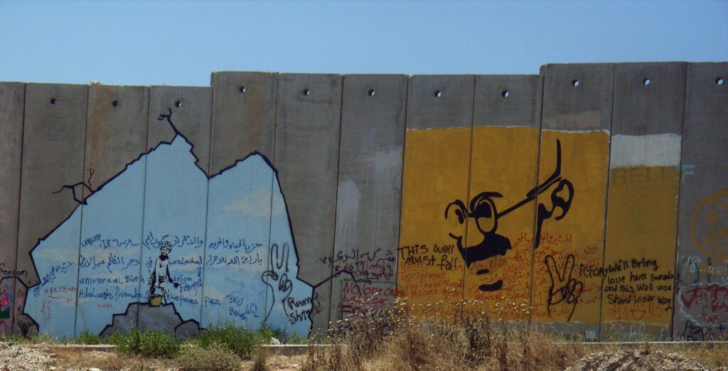 تصویری از مهاتما گاندی روی دیوار حائل در کرانه‌ی باختری
